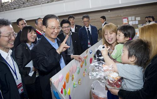 5月21日,中国国务院总理温家宝在日本福岛吾妻综合运动公园体育馆避难所慰问灾民。这是温家宝与避难所内的孩子亲切交流。新华社记者 黄敬文 摄