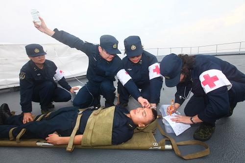 7月26日,医务人员在甲板上对“伤员”进行紧急救治。当日,中国海军“郑和”号远洋训练舰和“洛阳”号导弹护卫舰组成的训练舰编队在出访俄罗斯、朝鲜的航途中进行了战伤救护、心肺复苏等综合卫勤演练。演练过程中,海军总医院随舰出访医务人员和“郑和”号训练舰上的卫生人员紧密配合,在风急浪大、船体剧烈摇晃的情况下,克服晕船,对3名模拟心跳骤停、头部外伤、四肢骨折的伤员,进行了战位急救和舰上救护所紧急医疗救治。通过演练,医务人员进一步熟悉了战伤救治技术和危重急症救治的操作规程,提高了应急卫勤处置能力,强化锤炼了意志品质,为确保圆满完成出访任务打下了坚实的基础。新华社记者查春明摄