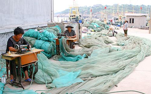 9月12日,浙江温岭市松门镇铜门村的渔民在修补渔网。 连日来,东海沿海渔民正抓紧时间,为即将到来的开渔做好准备。今年东海海域伏季休渔从5月1日中午12点起至9月16日中午12点结束。 新华社发(刘振清 摄)