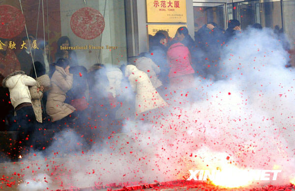 2月20日，大连一商家的职工在街头观看“开门炮”。