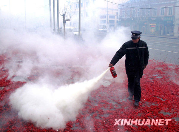 2月20日，大连一家商户的保安用灭火器处理燃放“开门炮”后留下的余烬。