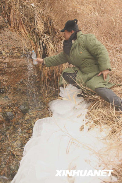  一位沙漠探险者在新疆库姆塔格沙漠大峡谷用矿泉水瓶接融雪水（2月20日摄）。