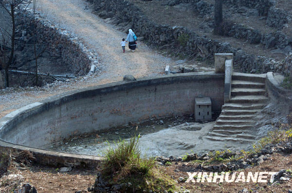 在广西隆林德峨乡常么村，老人和小孩牵手从一个已经干涸的水池旁走过（2月22日摄）。