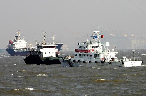 船舶航行在上海长江口外高桥码头水域(3月10日摄)。3月14日,国家“十一五”重点工程、我国最大的水运工程长江口深水航道三期治理工程通过交通运输部的验收。从东海到上海外高桥码头,打造出一条水深12.5米、全长92.2公里、底宽350米至400米的双向航道,拔掉了卡在长江口进出东海咽喉要道的“骨鲠”。长江口咽喉要道的打通,对于推动建设上海国际航运中心,充分发挥长江“黄金水道”的作用,带动长江三角洲和整个长江流域地区经济飞跃具有重要意义。新华社记者 陈飞 摄
