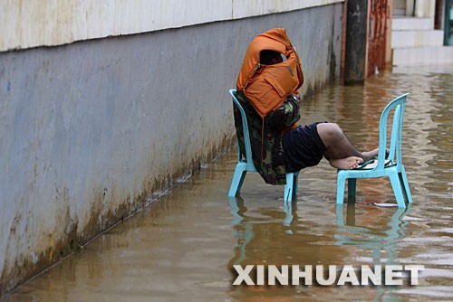 1月3日，在印度尼西亚首都雅加达，一名男子坐在被洪水淹没的街道中。