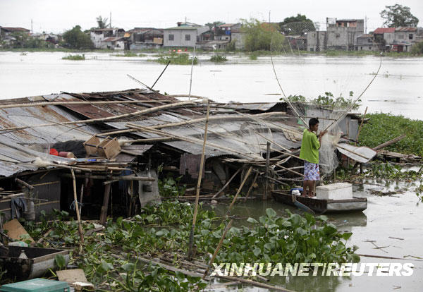 10月13日，在菲律宾首都马尼拉以东的一处受灾地区，一名当地人站在自家房屋的屋顶旁。菲律宾近日遭热带风暴“凯萨娜”和“芭玛”连续袭击，据救灾部门13日发布的一份报告说，目前已有超过600人丧生。