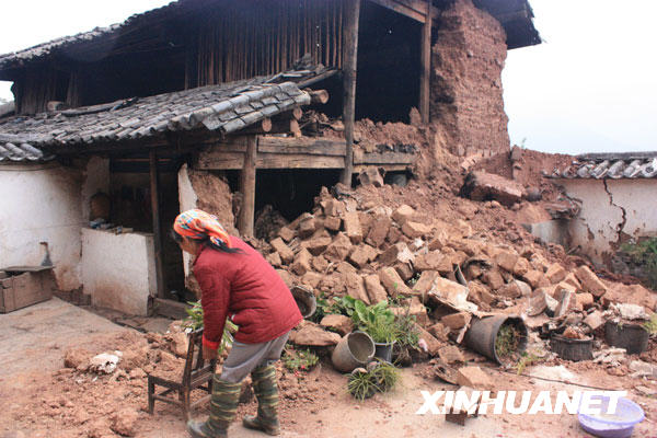 宾川县平川镇马花村的一位村民在受损的房屋前（11月2日摄）。