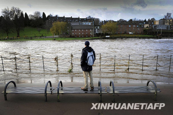11月22日，在苏格兰西南部邓弗里斯，一名男子看着泛滥的尼思河。连续的暴雨导致英国西北部地区一些河流水位上升，引发洪水警报。