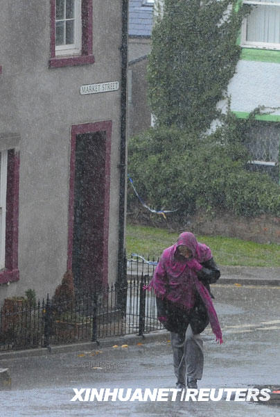  11月22日，在英格兰北部科克茅斯，一名妇女在大雨中行走。连续的暴雨导致英国西北部地区一些河流水位上升，引发洪水警报。