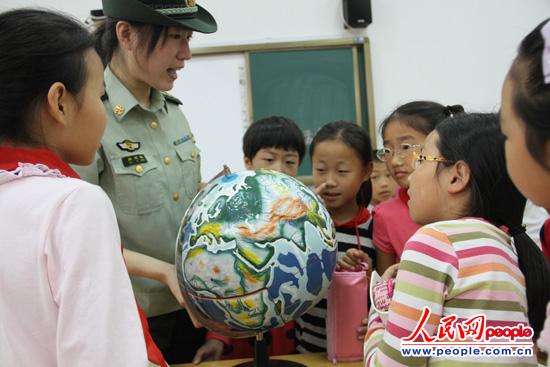 图为官兵在为孩子们讲解海洋知识