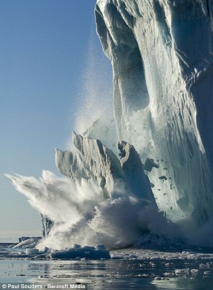 在格陵兰伊卢利萨特的一个阳光明媚的夏季傍晚，一大块冰从一座冰山上脱落下来