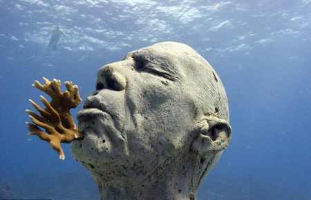 这尊雕塑描绘了一个孤独的人直挺地站着，嘴里咬着一块珊瑚礁。