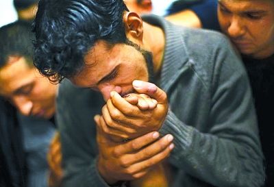 2012年11月18日，在加沙城的一家医院停尸间，一名巴勒斯坦男人亲吻死去亲人的手。第九届华赛年度新闻照片大奖在加沙告别贝尔纳特·阿尔曼戈摄